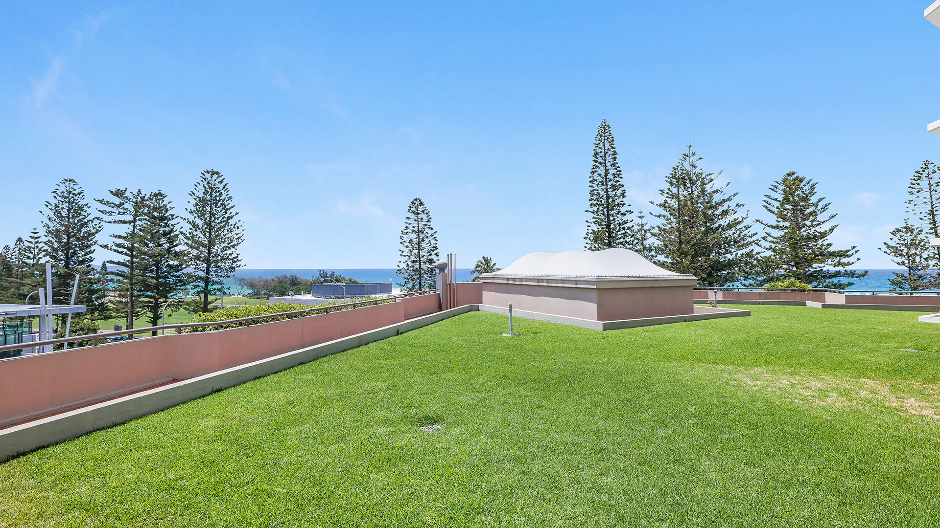 Expansive grassy courtyard area of the Superior 2 Bedroom Courtyard Apartment at ULTIQA Points North, with ocean glimpses and landscaped surroundings.