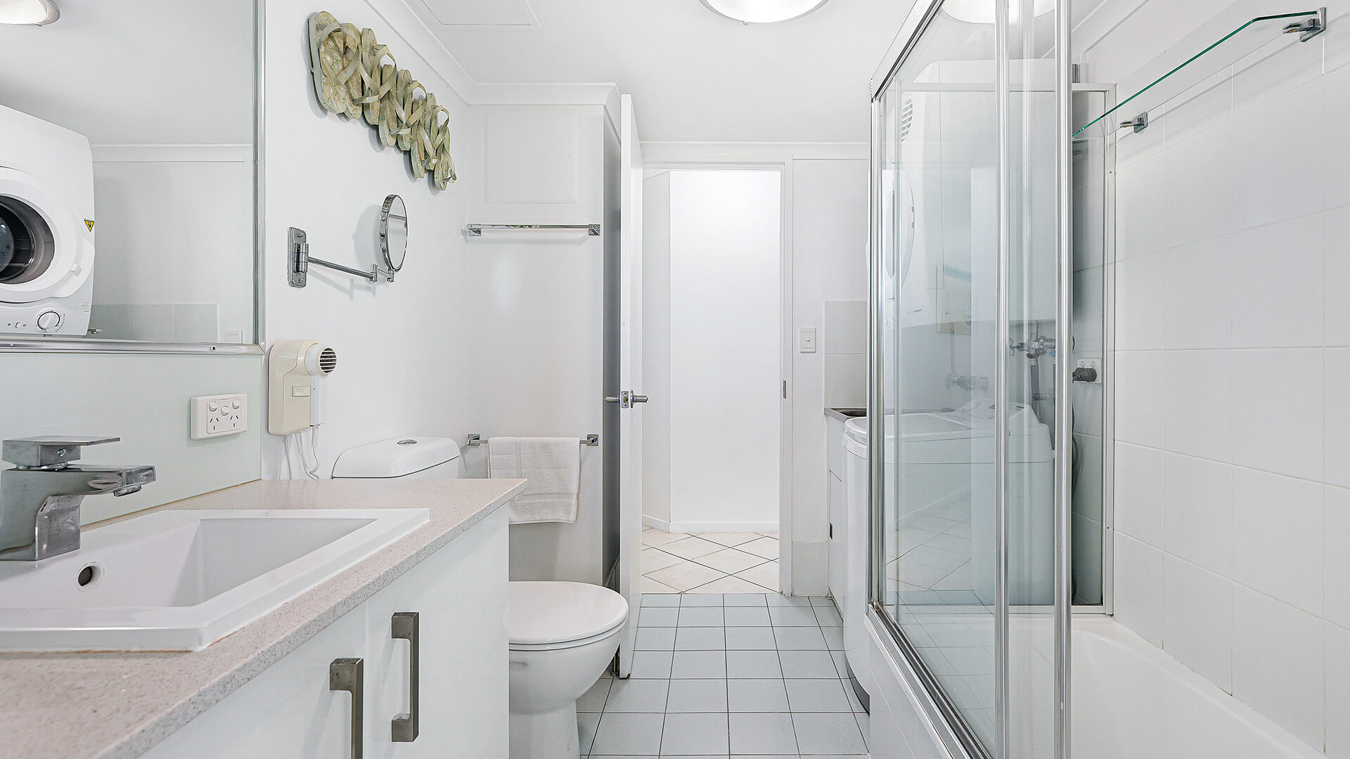 2nd bathroom in a 2 Bedroom Superior Ocean View Apartment with vanity, toilet, shower-over-bath with glass screens, in-room laundry, washer & dryer.