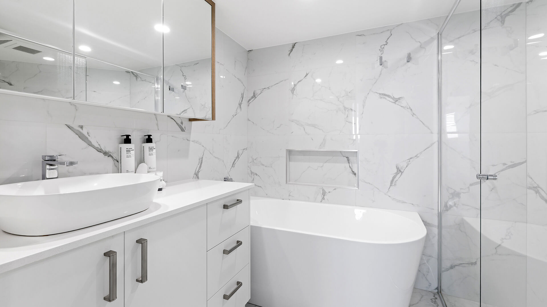 Modern bathroom in the Deluxe 3 Bedroom Ocean View Apartment, featuring a freestanding bath, walk-in shower & marble-style finishes.