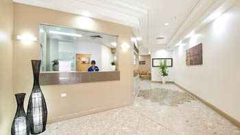 Reception area at ULTIQA Points North Coolangatta featuring the front desk, bright lighting, tiled floors, decorative vases & seating area.