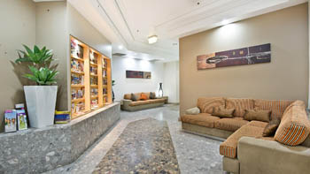 Lobby lounge area at ULTIQA Points North Coolangatta featuring striped sofas, a brochure display wall, modern décor, and tiled flooring.