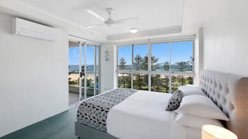 Bright master bedroom in the Standard 2 Bedroom Centre Front Apartment with ocean views and balcony access.