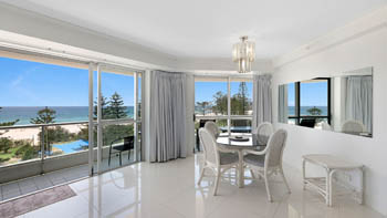 Dining area in the Standard 2 Bedroom Centre Front Apartment, featuring bright coastal views and balcony access.