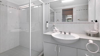 Bathroom in the Standard 2 Bedroom Centre Front Apartment featuring a walk-in shower and ample vanity space.