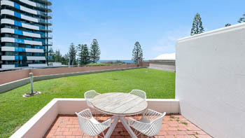 Private courtyard area in the Superior 2 Bedroom Courtyard Apartment at ULTIQA Points North, featuring outdoor seating and partial ocean views.