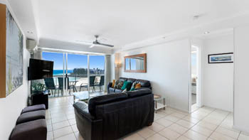 Coastal living area in the 2 Bedroom Superior Ocean View Apartment with leather sofas, tiled floors, balcony access with ocean and beach views.