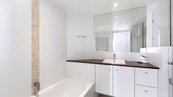 Bathroom in the Superior 3 Bedroom Ocean View Apartment featuring a bathtub, large mirror, and modern vanity with ample counter space.