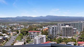 Sweeping hinterland view featuring lush greenery and distant mountain ranges under a bright blue sky.