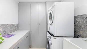 Laundry room in the 4 Bedroom Oceanfront Penthouse at ULTIQA Points North with washer, dryer, and storage cabinets.