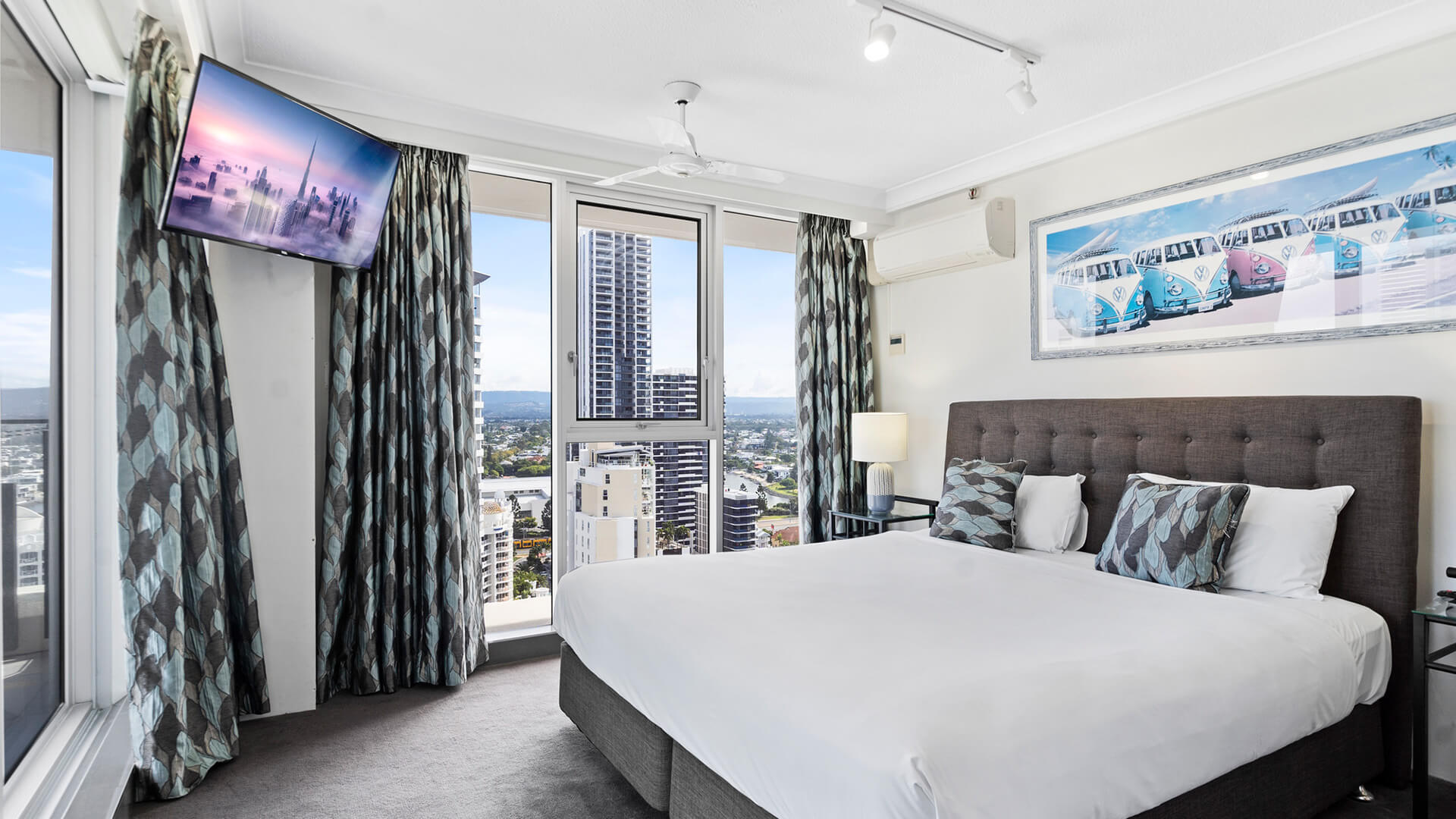 Master bedroom with dark headrest, whit plush bedding and a view of the Gold Coast at ULTIQA Beach Haven.