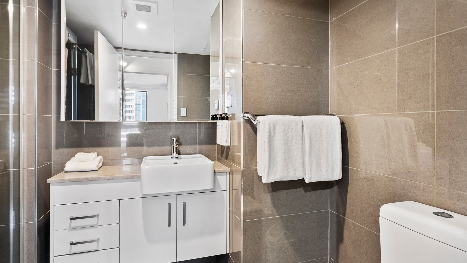 Second bathroom with clean white towels, sink and a toilet in modern style at ULTIQA Beach Haven.