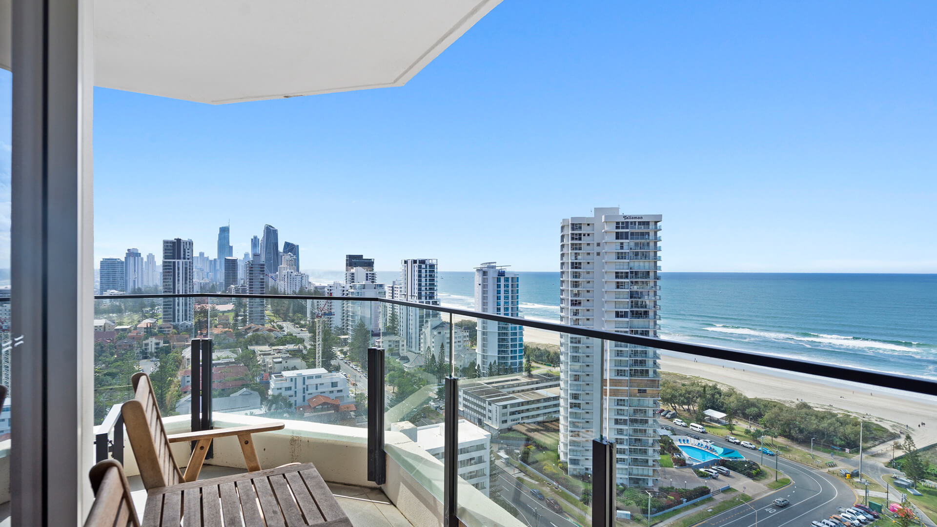 View of Broadbeach from the balcony at ULTIQA Beach Haven with a nice wooden outside furniture set of a table and two chairs. 