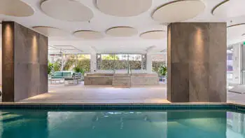 Heated indoor pool and spa area at ULTIQA Beach Haven on Broadbeach, featuring elegant tiled finishes, lounge seating, and natural light - perfect for year-round relaxation.