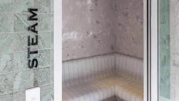 Modern tiled steam room at ULTIQA Beach Haven on Broadbeach, featuring curved seating and soft lighting for a tranquil wellness experience.