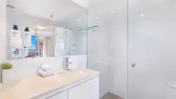 Modern bathroom in the 2 Bedroom Ocean View Apartment at ULTIQA Beach Haven on Broadbeach featuring a spacious walk-in shower, large mirror, and sleek vanity with fresh towels and amenities.