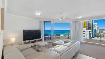 Living room in the 2 Bedroom Ocean View Apartment at ULTIQA Beach Haven on Broadbeach with large sectional sofa, flat-screen TV, and ocean-facing balcony.