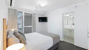 Master bedroom at ULTIQA Beach Haven on Broadbeach featuring a king bed, flat-screen TV, air conditioning, and direct access to a private ensuite.