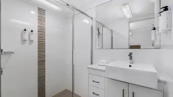 Modern bathroom at ULTIQA Beach Haven on Broadbeach featuring a walk-in shower, large vanity, and mirrored cabinetry with complimentary amenities.
