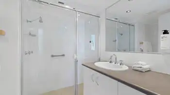 Main bathroom in the Standard 2 Bedroom Ocean View Apartment at ULTIQA Beach Haven on Broadbeach, featuring a glass shower, large mirror, and vanity.