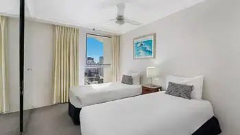 Second bedroom in the Standard 2 Bedroom Ocean View Apartment at ULTIQA Beach Haven on Broadbeach, featuring two single beds and city views.