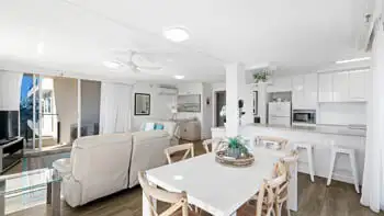 Standard 2 Bedroom Ocean View Apartment with open-plan living, dining, and kitchen area at ULTIQA Beach Haven on Broadbeach, featuring modern furnishings, a white interior, and natural light.