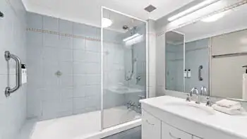 Main bathroom in the Standard 2 Bedroom Ocean View Apartment at ULTIQA Beach Haven on Broadbeach, featuring a combined shower and bathtub, large mirror, and tiled walls.