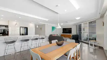 Spacious dining and living featuring a breakfast bar, modern lighting, and private balcony access.