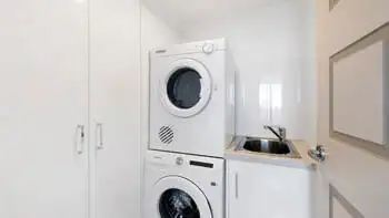 Fully equipped laundry in the Sub Penthouse at ULTIQA Beach Haven on Broadbeach, featuring a washer, dryer, and sink.