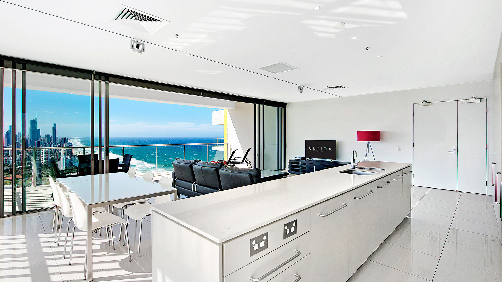 Modern kitchen and dining area flowing into a spacious lounge with panoramic ocean and city views from the 2 Bedroom Gold Coast View Suite at ULTIQA Air on Broadbeach.