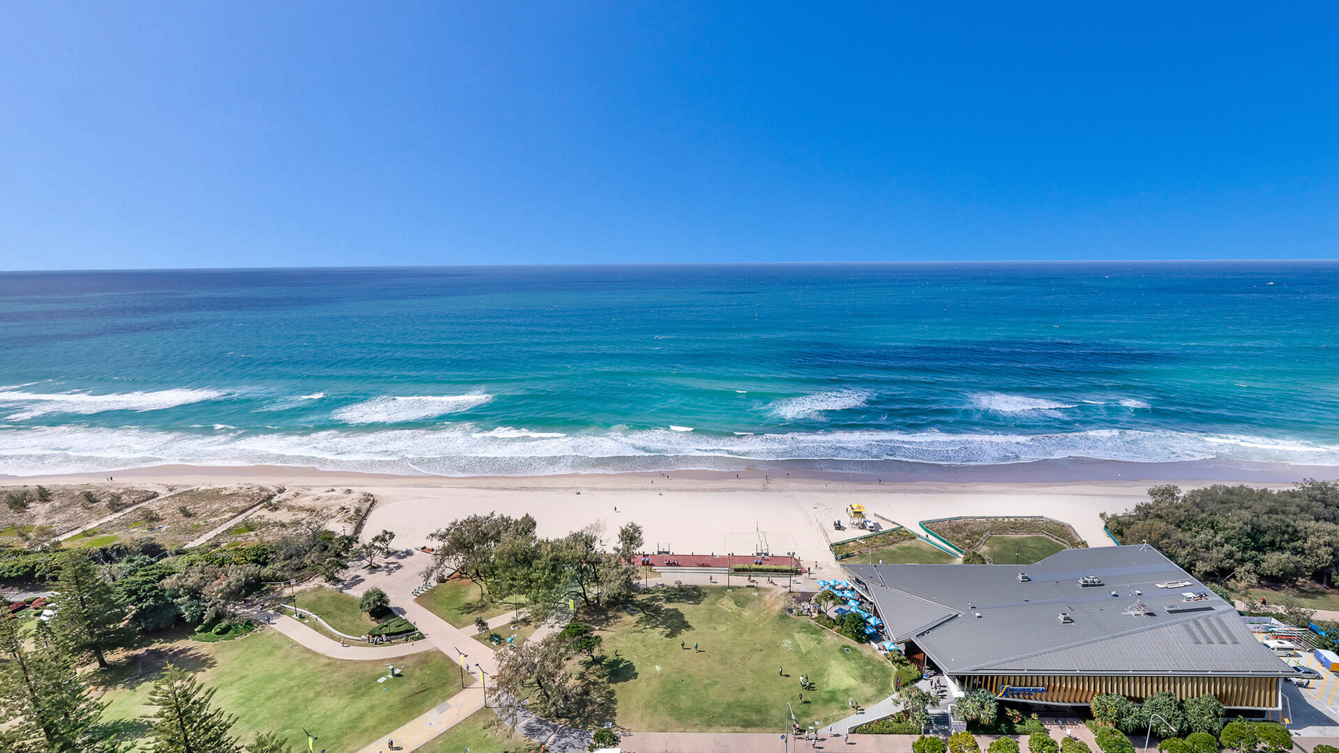 Aerial view of Kurrawa Beach and coastline from 2 Bedroom Ocean View Apartment at ULTIQA Air on Broadbeach, overlooking the surf club and parklands.