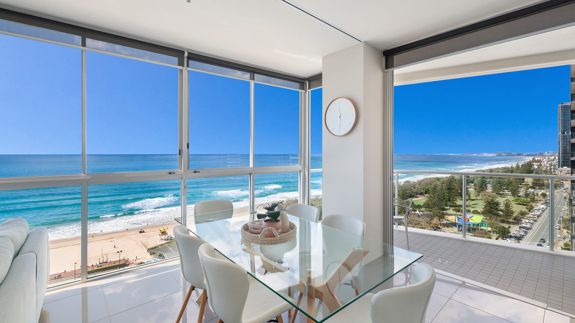 Dining area with glass table and balcony access, featuring panoramic ocean and park views in 2 Bedroom Ocean View Suite at ULTIQA Air on Broadbeach.