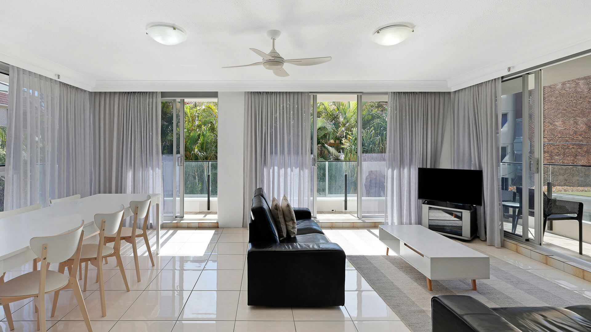 Spacious living and dining area with TV and floor-to-ceiling windows in the 2 Bedroom Apartment at ULTIQA Beach Haven.