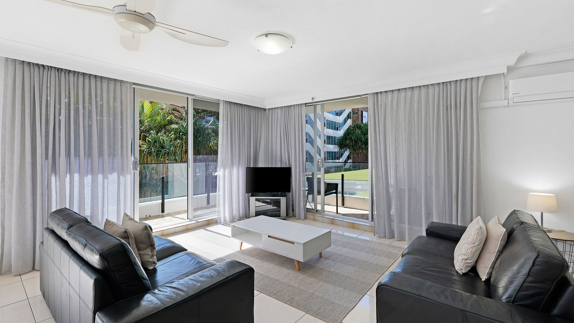 Living area with leather sofas and access to outdoor balcony in the 2 Bedroom Apartment at ULTIQA Beach Haven.