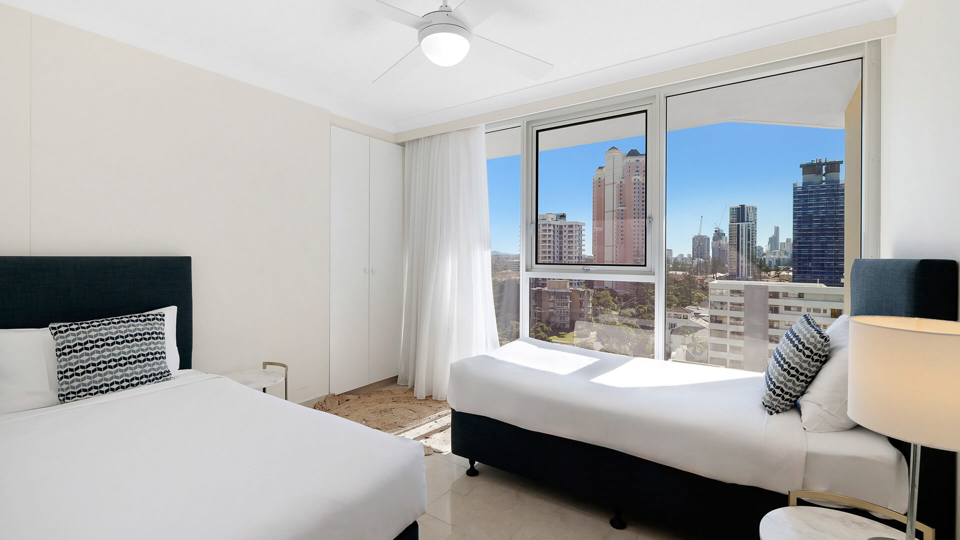 Second bedroom in the Standard 2 Bedroom Ocean View Apartment at ULTIQA Beach Haven featuring a queen and single bed with city views.