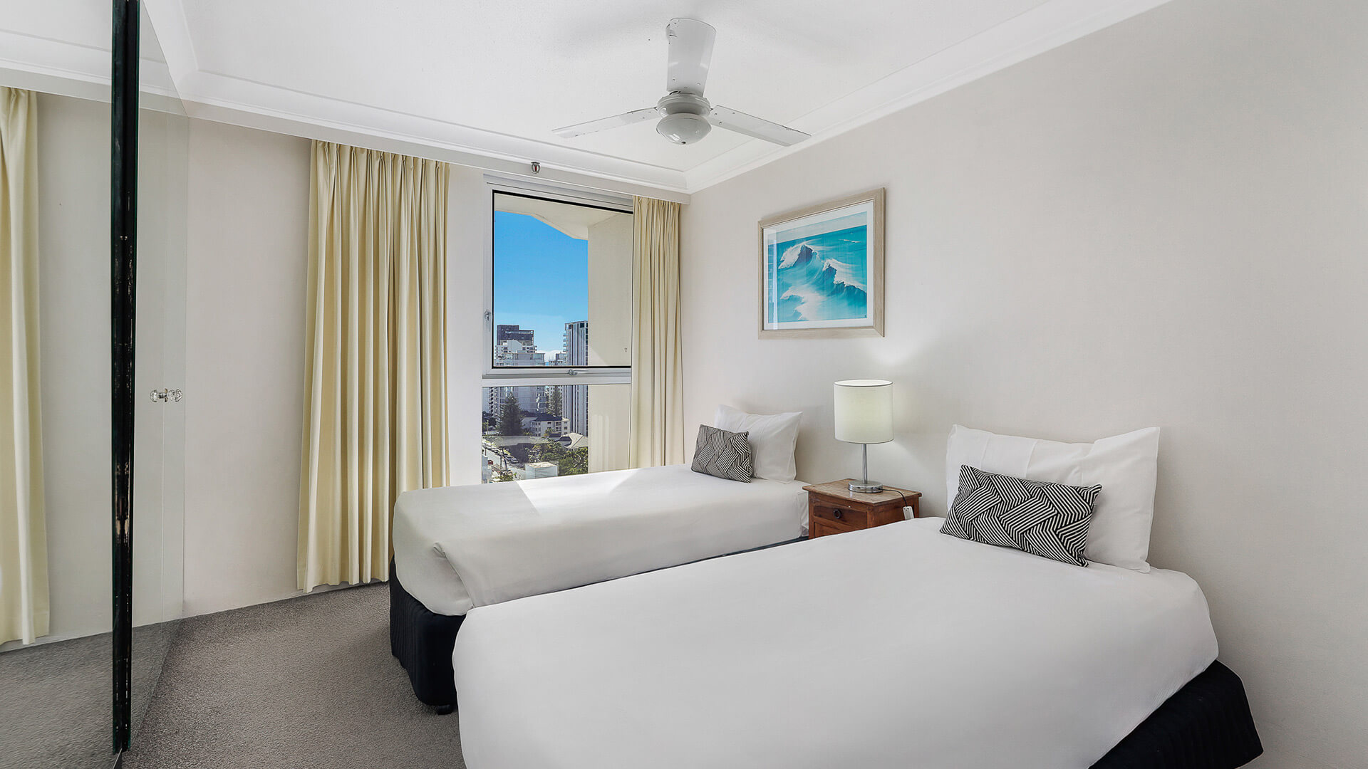 Second bedroom in the Standard 2 Bedroom Ocean View Apartment at ULTIQA Beach Haven, featuring two single beds and city views.