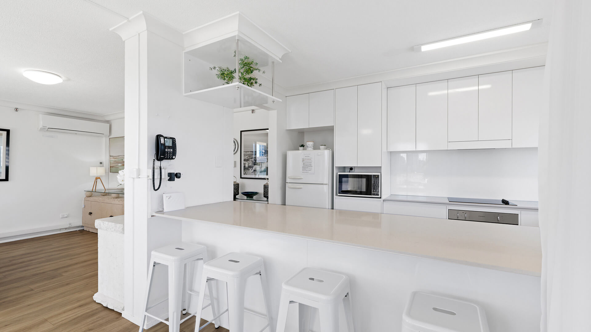 Spacious kitchen with white cabinetry, full-size fridge, and breakfast bar seating in the Standard 2 Bedroom Ocean View Apartment at ULTIQA Beach Haven.