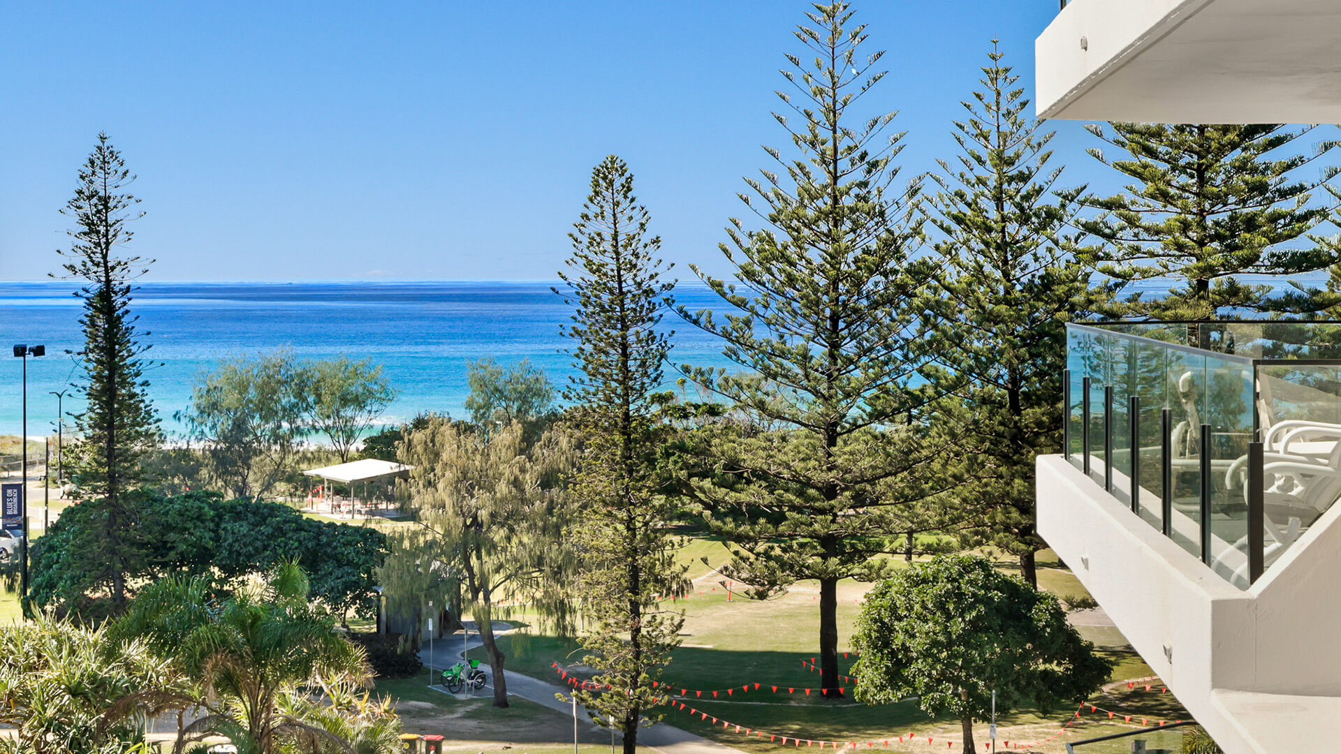 Ocean views from ULTIQA Beach Haven with parklands, towering pine trees, and turquoise water visible from the resort.
