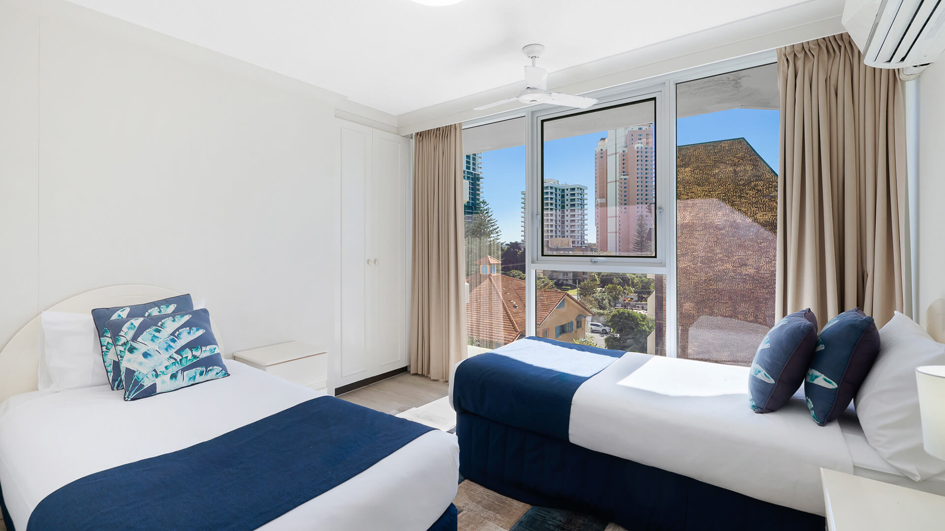 Second bedroom in the 2 Bedroom Ocean View Apartment at ULTIQA Beach Haven with two single beds and large window.