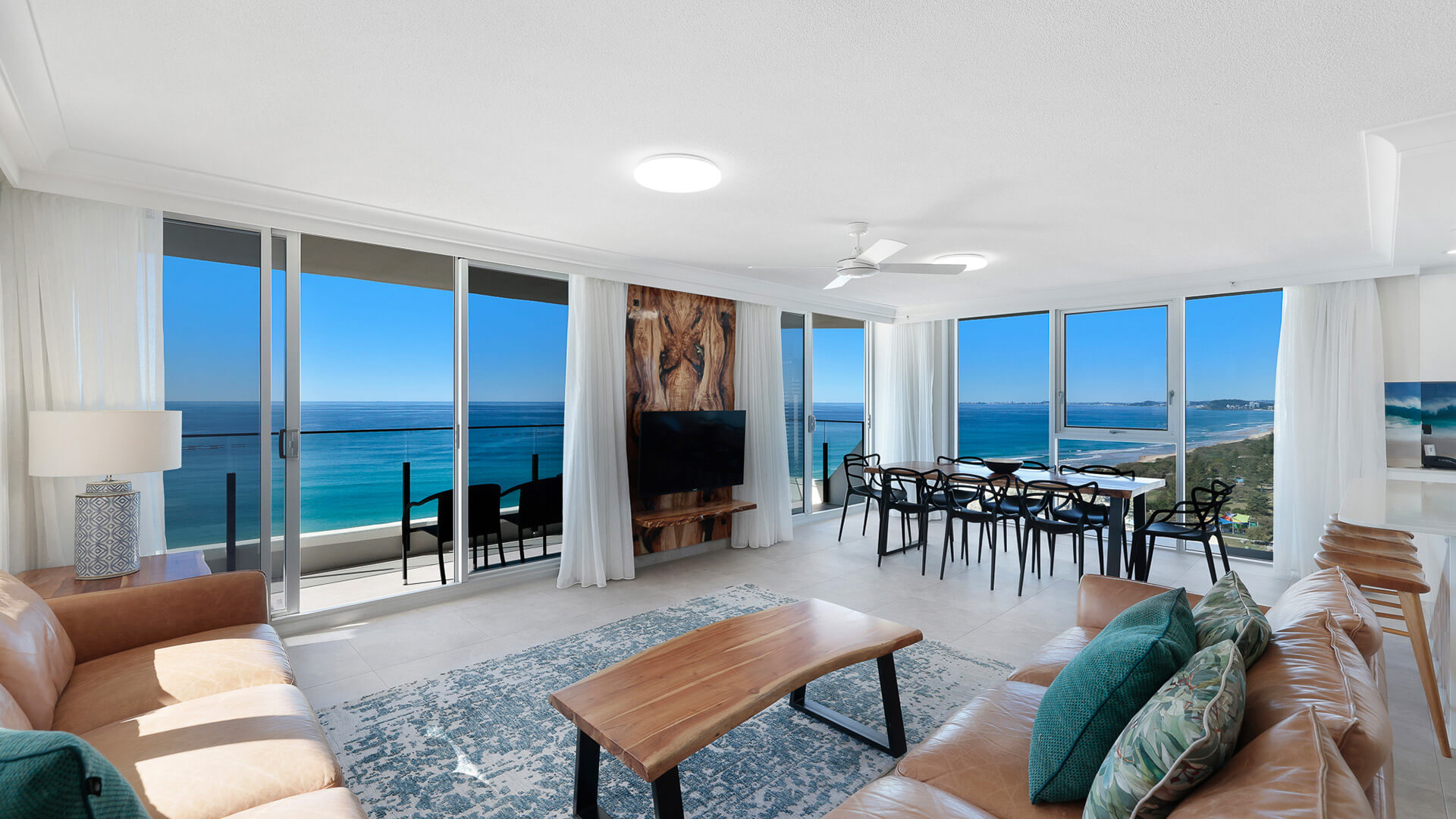 Ocean-view living and dining area with leather lounges, coastal accents, and panoramic views from Broadbeach to Burleigh.