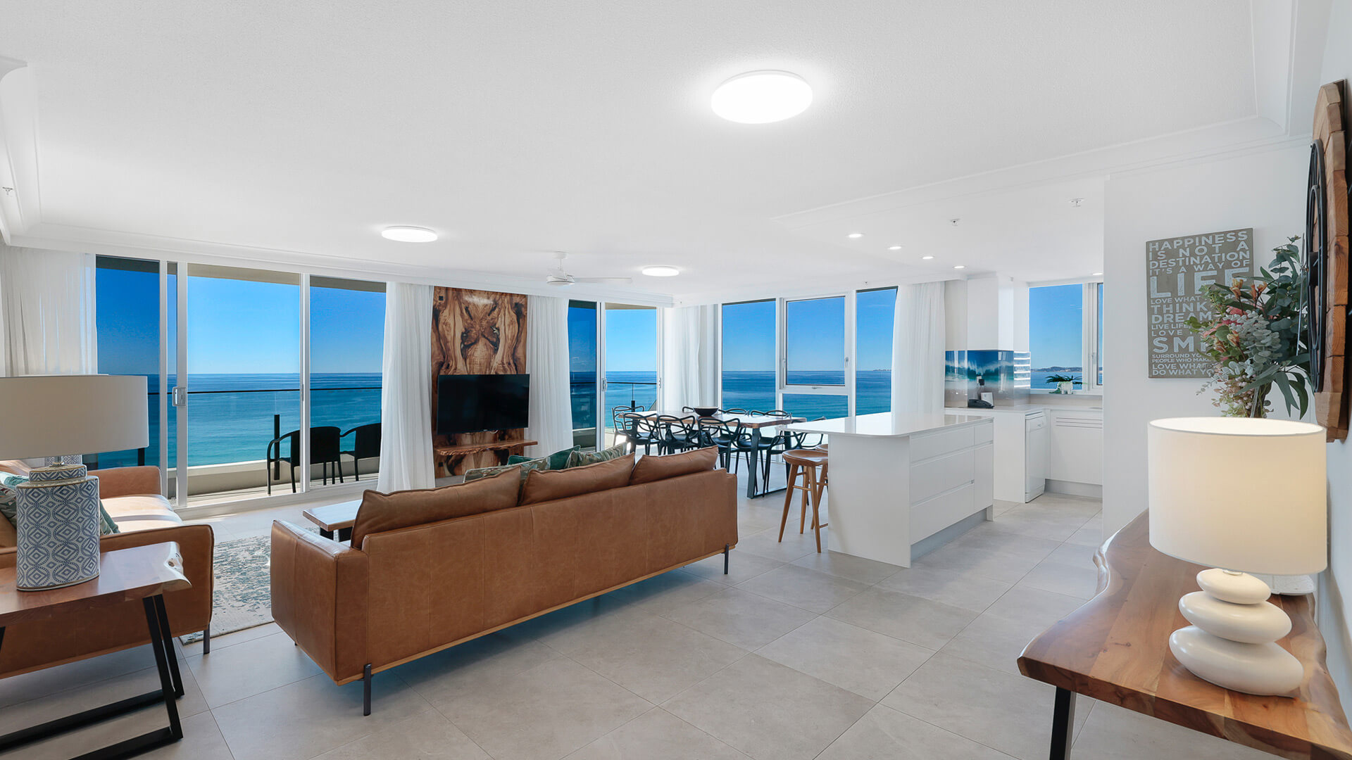 Spacious open-plan featuring leather lounges, a modern kitchen, ocean-facing dining area, and stunning coastal views from every angle.