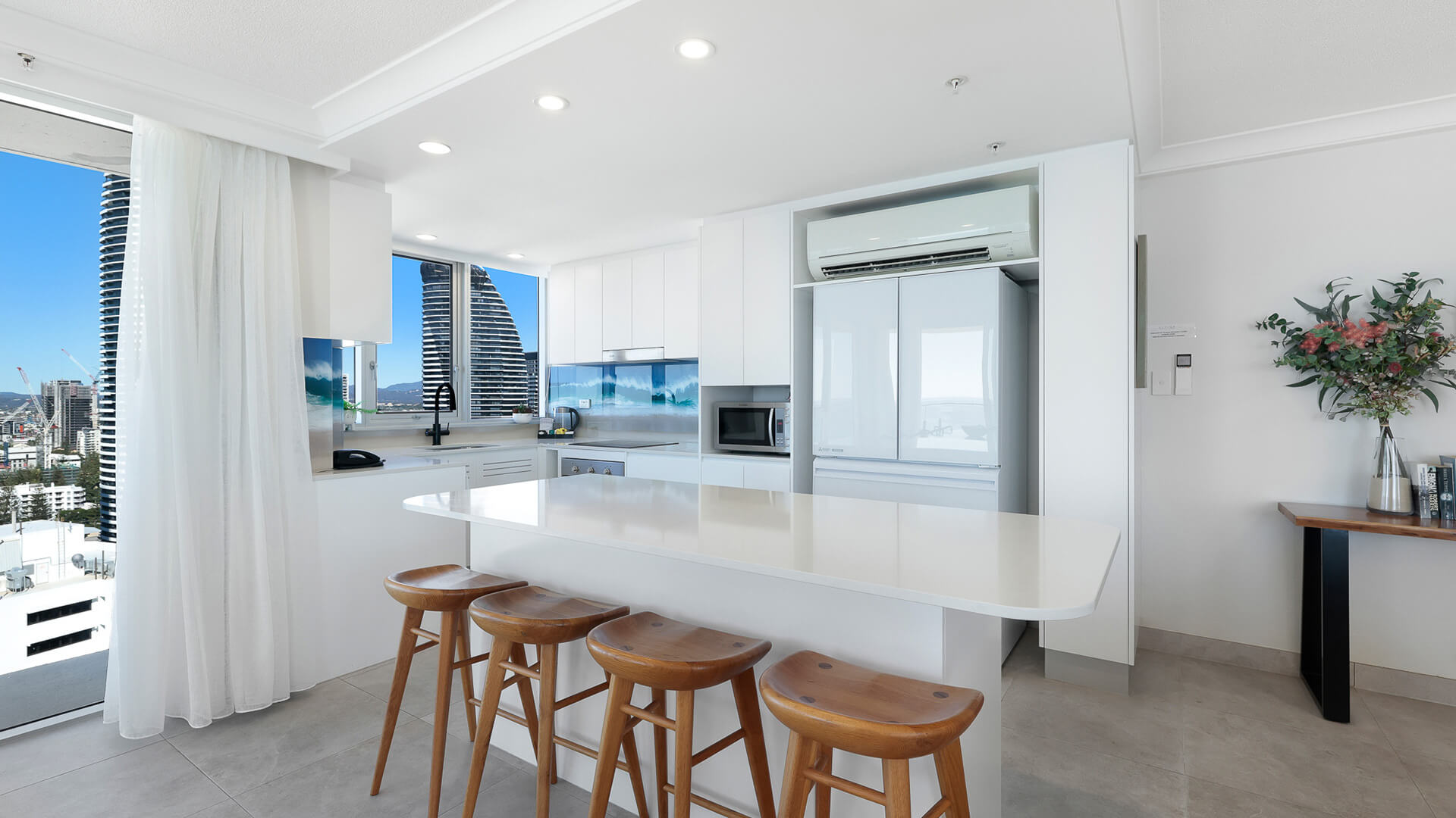 Modern kitchen in the Premium 2 Bedroom Ocean View Apartment at ULTIQA Beach Haven with island bench, timber stools, and skyline views.