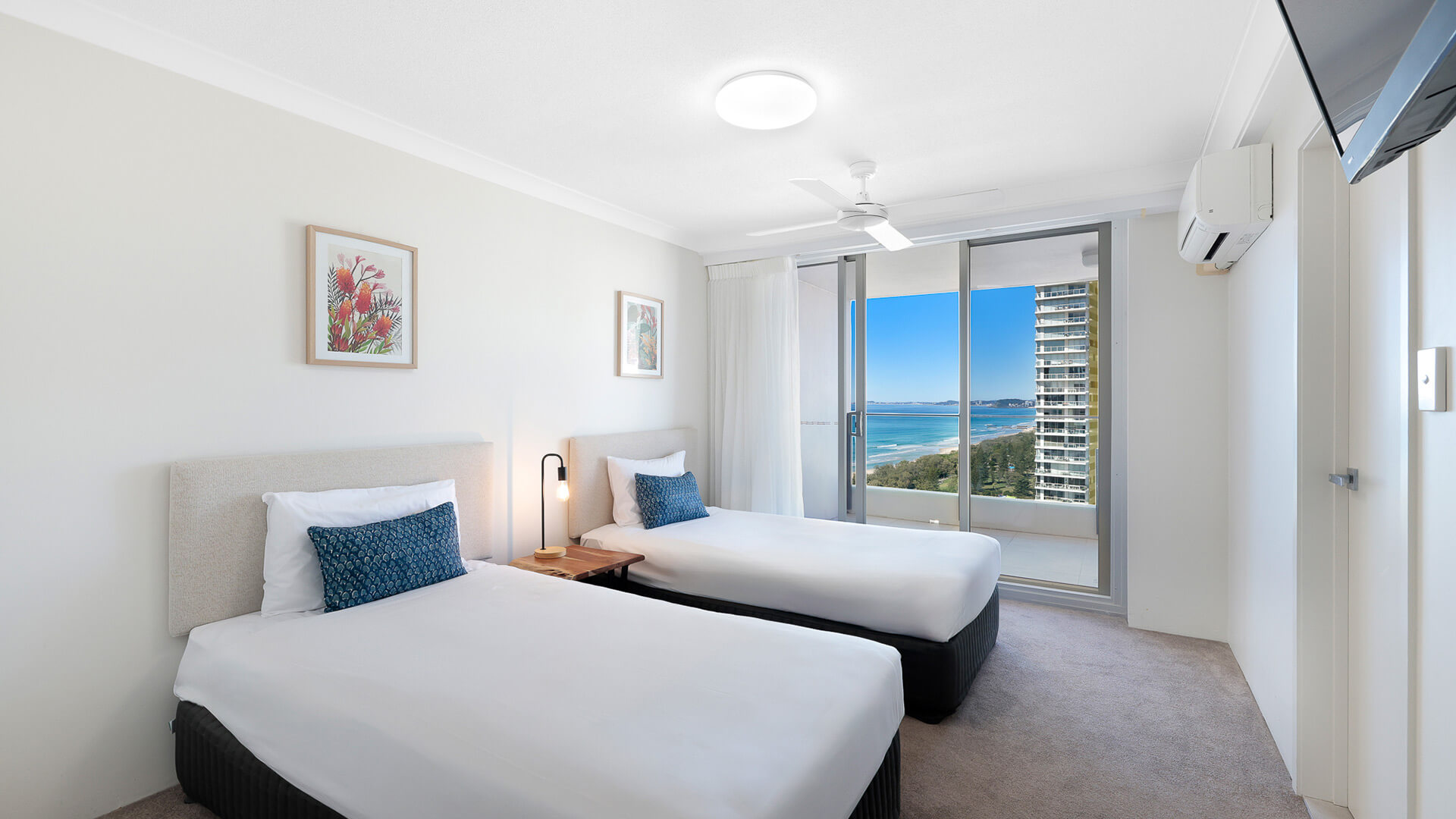 Second bedroom in the Premium 2 Bedroom Ocean View Apartment at ULTIQA Beach Haven, featuring two single beds and ocean-facing balcony access.
