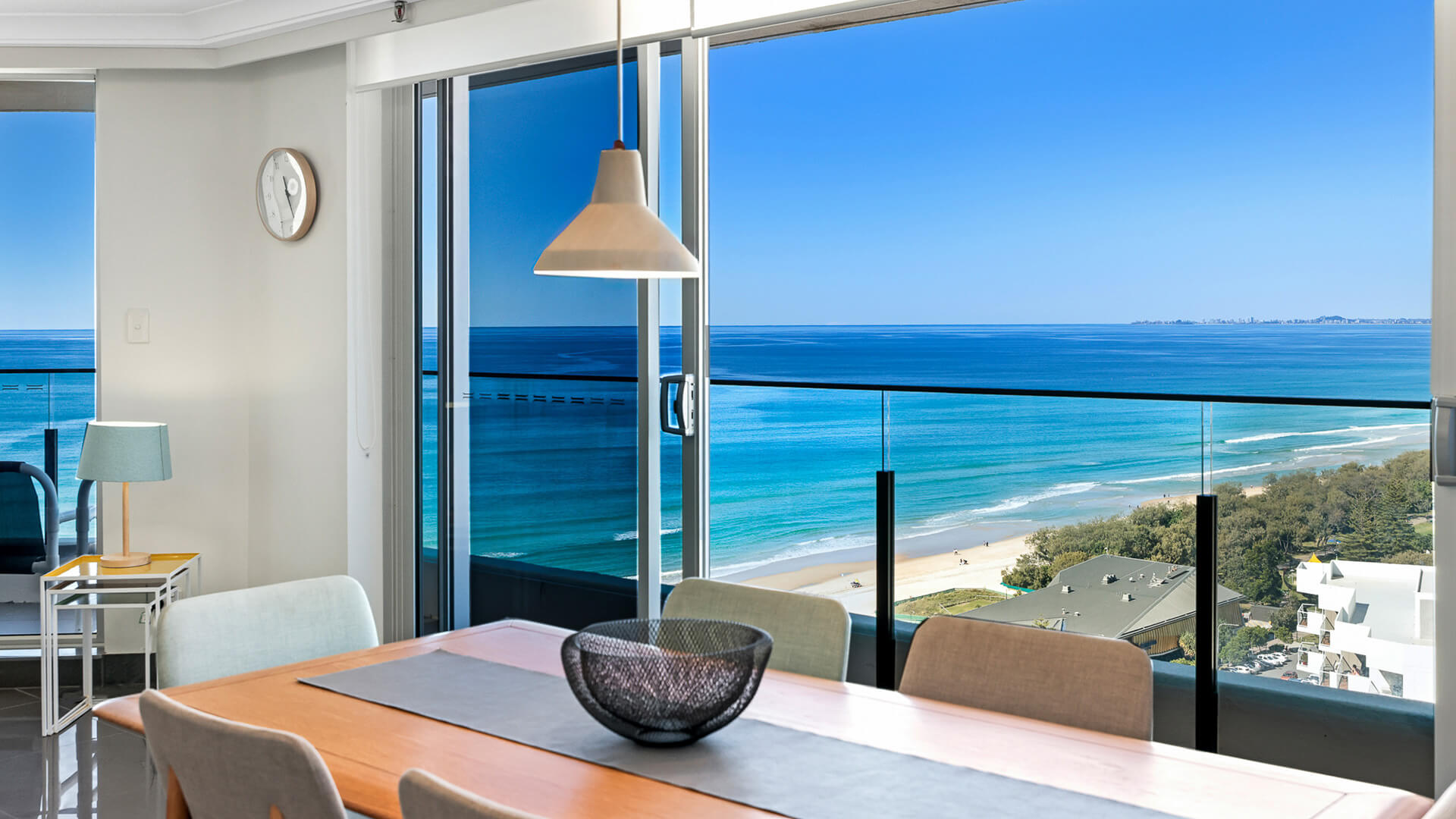 Close-up of the dining table with breathtaking views of the Gold Coast shoreline through floor-to-ceiling windows.