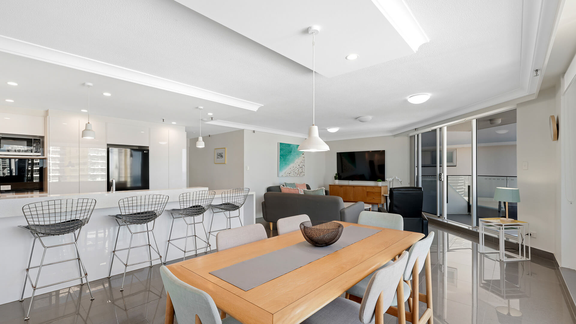 Spacious dining and living featuring a breakfast bar, modern lighting, and private balcony access.