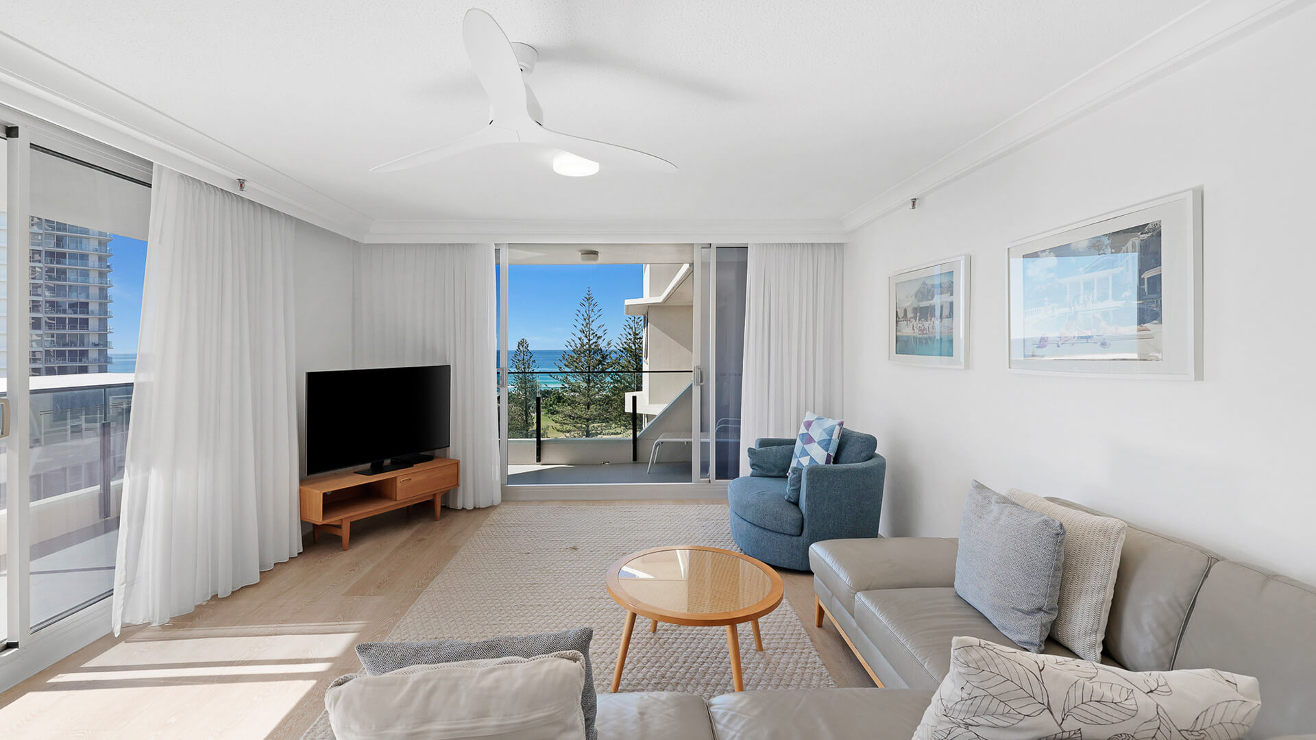 Bright and airy living featuring a modern lounge suite, flat-screen TV, and private balcony with ocean views.