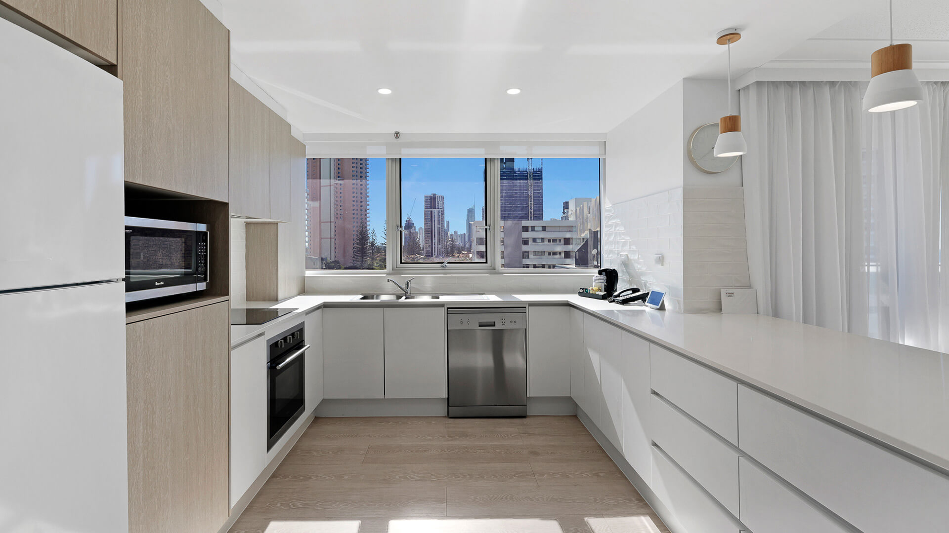 Modern fully equipped featuring sleek cabinetry, stainless steel appliances, and large window with city views.