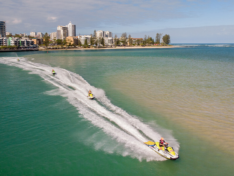 Jet skis speeding across the water with Caloundra's coastline in the background.