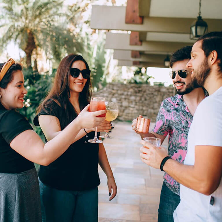 Group of friends enjoying drinks together outdoors at a resort.