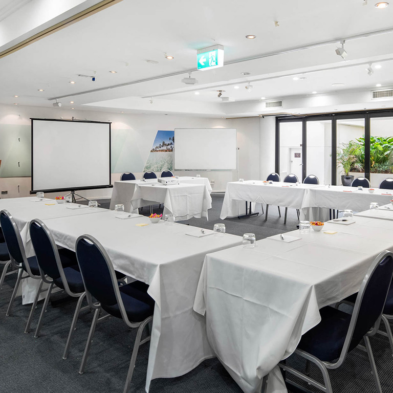 Modern conference room at ULTIQA Shearwater Resort with U-shaped setup, natural light, and AV facilities.