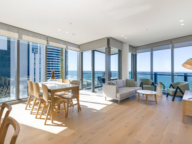 Modern ocean-view apartment living and dining area with floor-to-ceiling windows at ULTIQA Signature at Broadbeach.